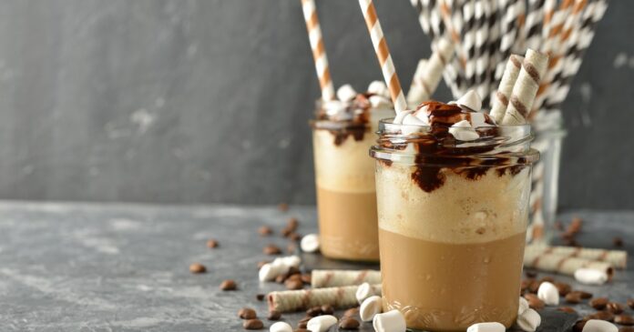Vaso alto de café frappé de chocolate decorado con crema, salsa y chocolate rallado.