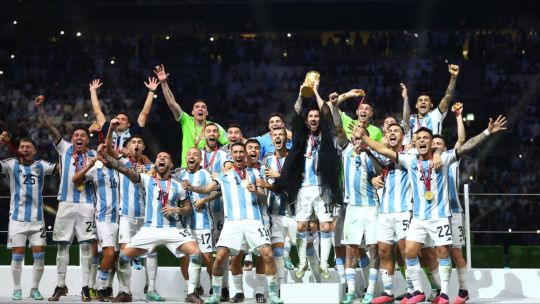 Jugadores de la Selección Argentina celebran el título mundial sosteniendo la Copa del Mundo.