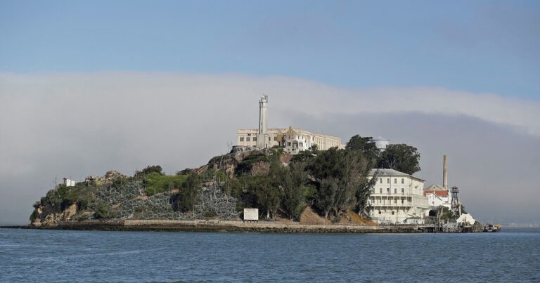 Isla de Alcatraz con el muelle principal en reparación y turistas observando desde un ferry