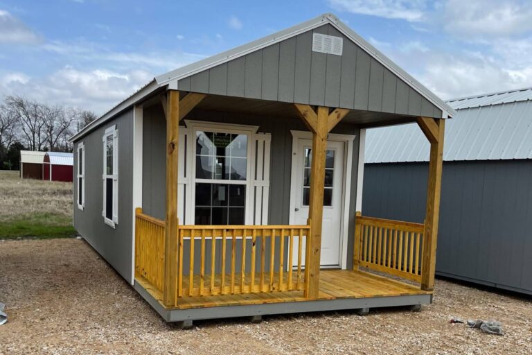 Casa prefabricada tipo cabaña de color blanco con porche, modelo Lake House Tiny Home Cabin.