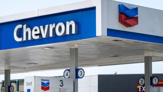 Logotipo de Chevron frente a una refinería o instalación petrolera