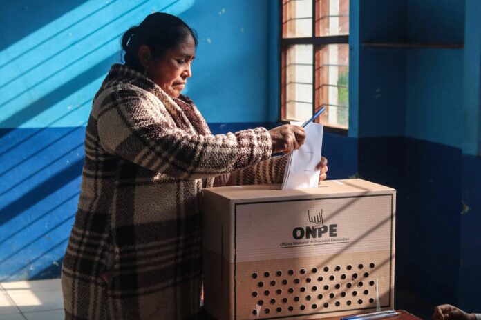 Votantes formados en una larga fila frente a un centro de votación en Lima, Perú.