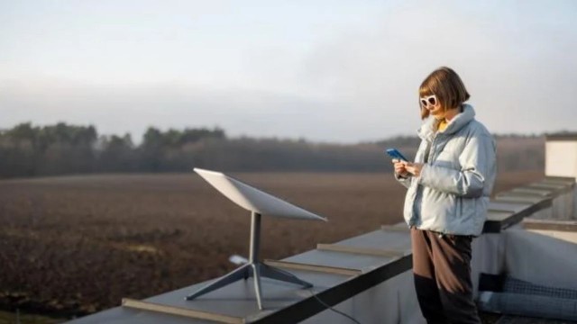 Persona usando una tablet para realizar una prueba de velocidad a un plato satelital Starlink en el exterior