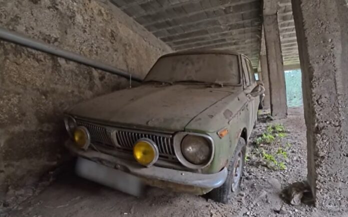 exploradores-galpon-autos-clasicos-japoneses-abandonados-portugal Interior de un galpón abandonado con varios autos clásicos japoneses cubiertos de polvo.