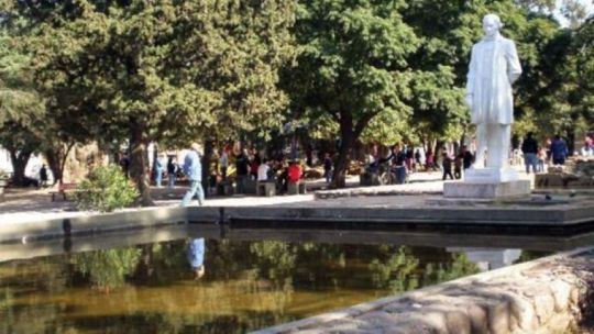 Plaza pública con contenedores de residuos y bolsas de basura en el suelo.