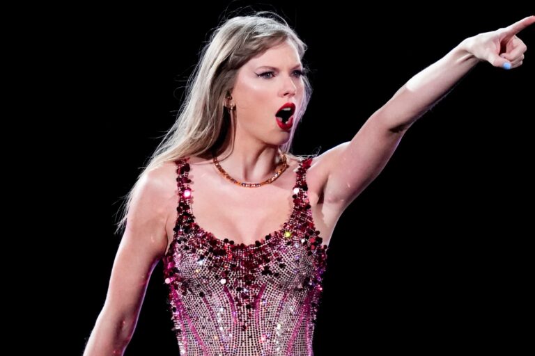 Taylor Swift sosteniendo una guitarra rosa en un escenario