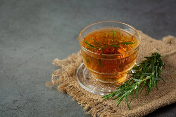 Taza de té de clavo de olor y laurel con hojas y clavos sobre una mesa de madera