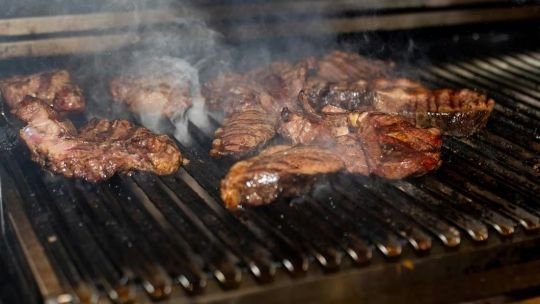 Asado en parrilla con cortes de carne, ensaladas y bebidas