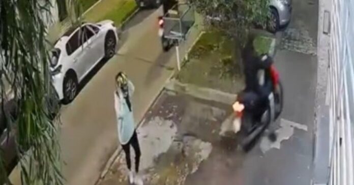 Mujer junto a su moto en la vía pública