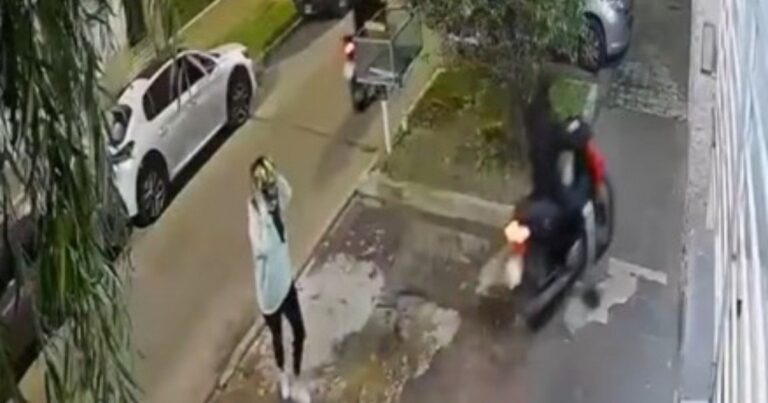 Mujer junto a su moto en la vía pública