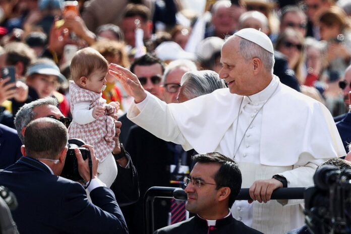 El papa León XIV bendice a un bebé durante su recorrido en papamóvil en Madrid