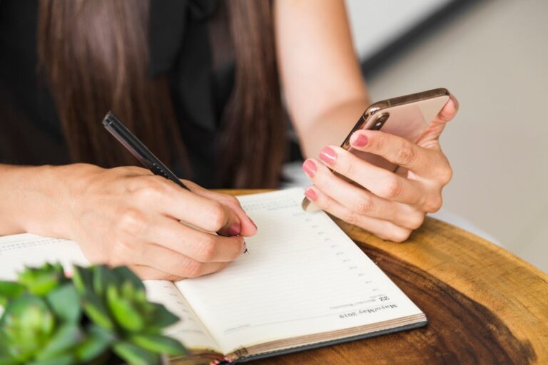 Persona escribiendo en una agenda de papel con un bolígrafo