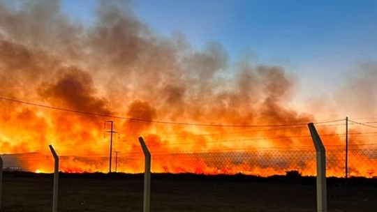 Bomberos trabajando en el control de un incendio de pastizales en barrio Docta, Córdoba