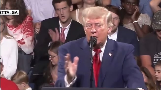 Imitador de Donald Trump haciendo gestos detrás del presidente durante un acto de campaña en Georgia