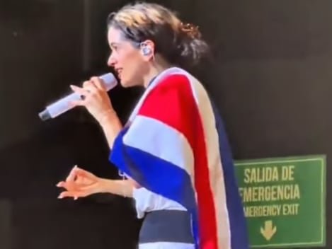 Rosalía con la bandera de Costa Rica sobre el hombro durante concierto en Bogotá