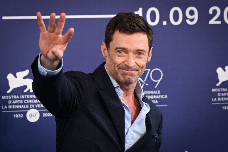 Hugh Jackman realizando sentadilla con banda elástica en el gimnasio