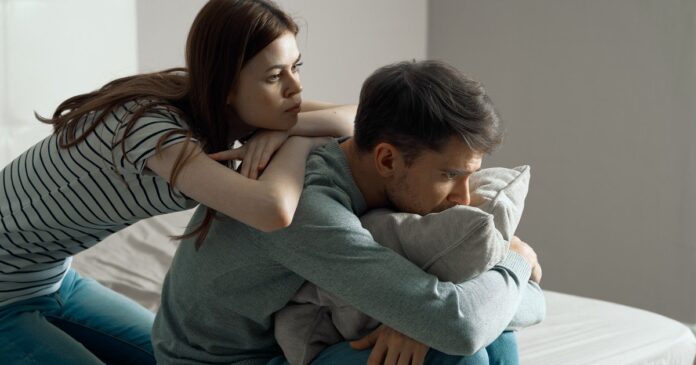 Pareja conversando en un sillón, con actitud de cuidado y atención mutua.