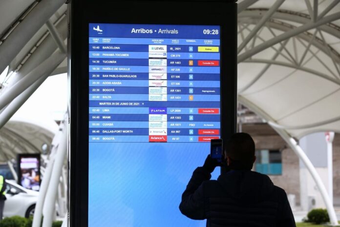 Aeropuerto con pasajeros y pantalla de vuelos