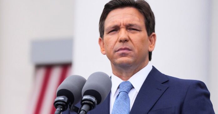 Ron DeSantis hablando en un atril con el logo de Florida de fondo